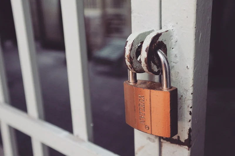 A brass padlock on a white gate